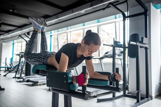 Sportliches Mädchen zeigt ihren gut trainierten Körper im Fitnessstudio, wo es viele neue Trainingsgeräte gibt