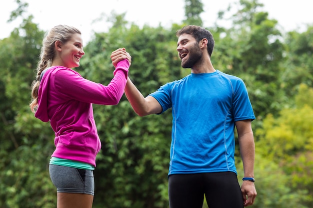 Sportliches Paar, das Hände im Wald hält