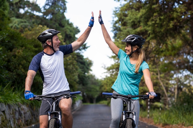 Sportliches Paar, das hohe fünf beim Fahrradfahren auf der Straße gibt