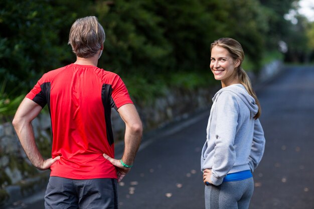 Sportliches Paar, das mit den Händen auf der Hüfte auf der Straße steht