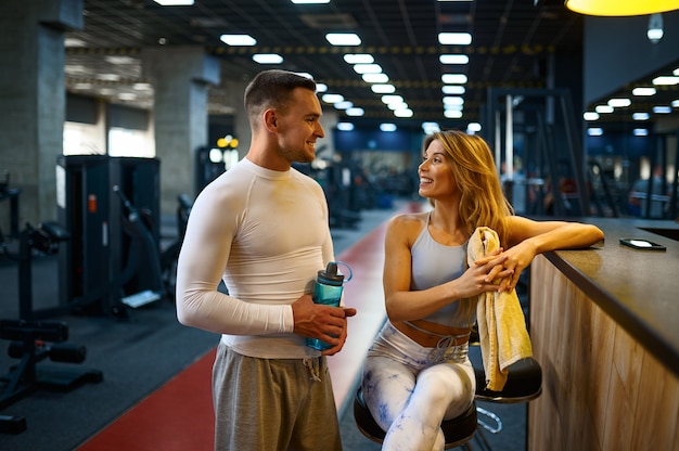 Sportliches Paar entspannt sich nach dem Fitnesstraining an der Theke in der Fitnessbar