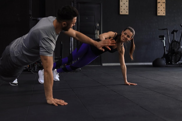 Foto sportliches paar macht liegestütze und gibt sich im fitnessstudio high five.