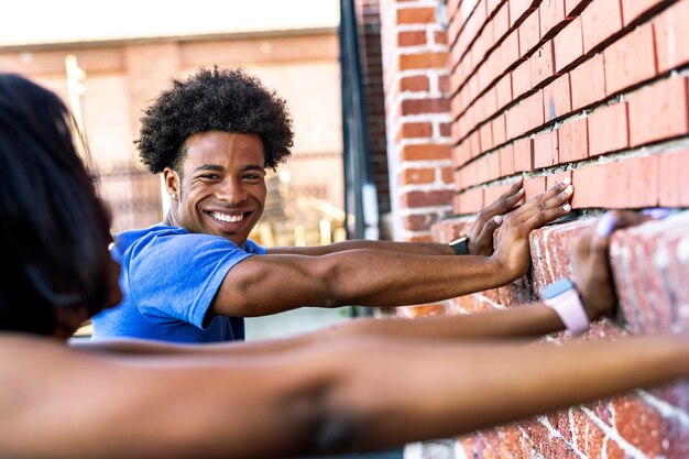 Sportliches Paar streckt sich gegen eine Mauer