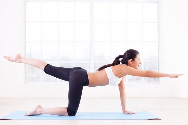 Sportliches Training. Seitenansicht der schönen jungen indischen Frau, die auf Yogamatte trainiert