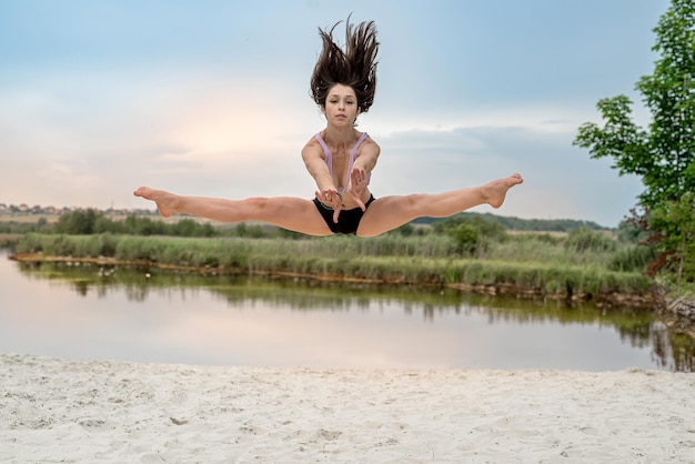 Sportmädchen machen Yoga oder streichen sich am See Sandstrand Sommerzeit