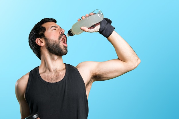 Sportman fazendo levantamento de peso bebendo refrigerante de água em fundo colorido