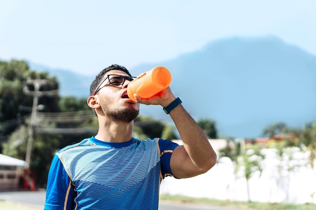 Sportmann trinkt in einer orangen flasche mit bpa frei