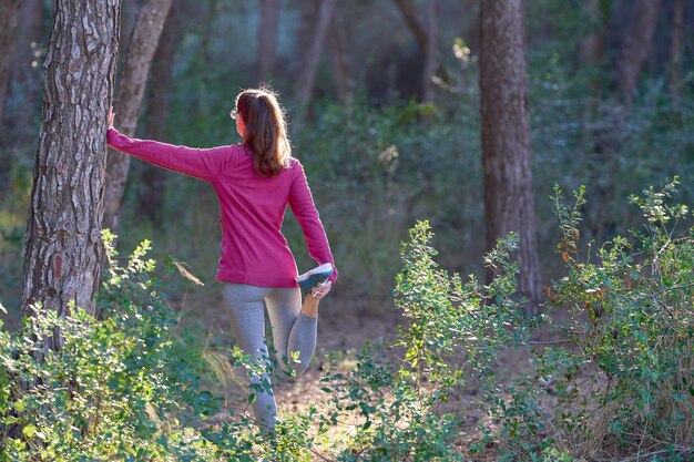 Sports Woman estira las piernas antes de correr por el bosque