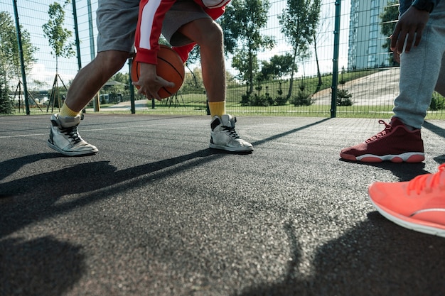 Sportspiele. Schließen Sie oben von einem orangefarbenen Ball, der in den Händen des Basketballspielers ist