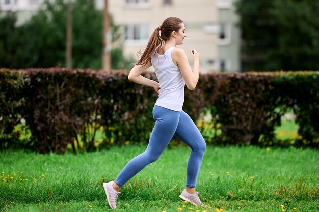 Sporttraining einer Läuferin im öffentlichen Park neben einem Wohngebiet und einem Wohnhaus