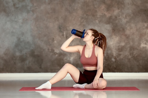 Sportwasserflasche in der Frauenhand im Yogastudio