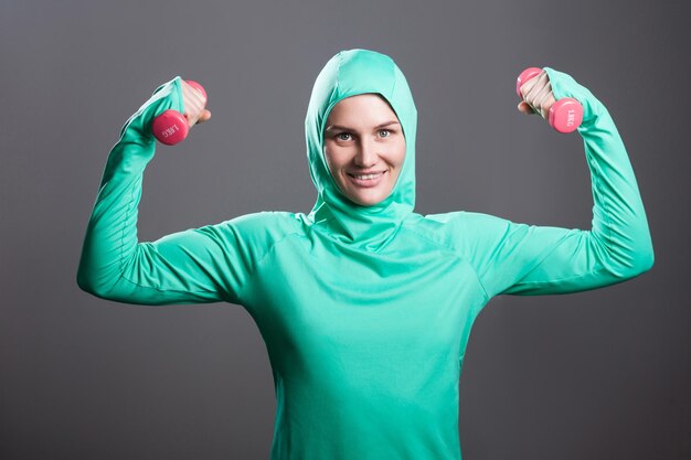 Sportwoman en ropa deportiva verde sobre fondo gris