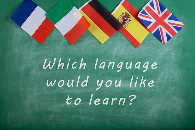 Sprachlernkonzept - Flaggen von Spanien, Frankreich, Großbritannien, Russland und Italien und Tafel mit Text "Welche Sprache möchten Sie lernen?"