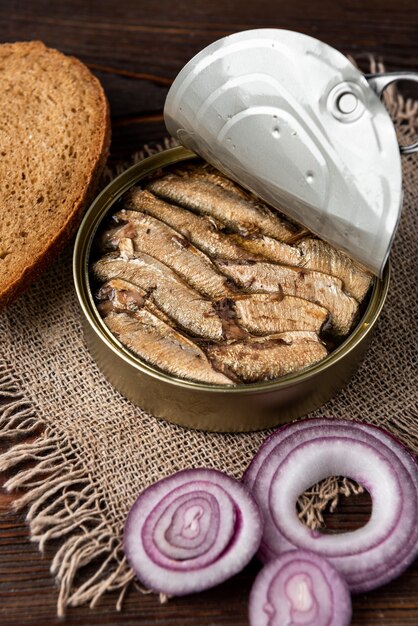 Sprats em uma lata e pão na mesa de madeira