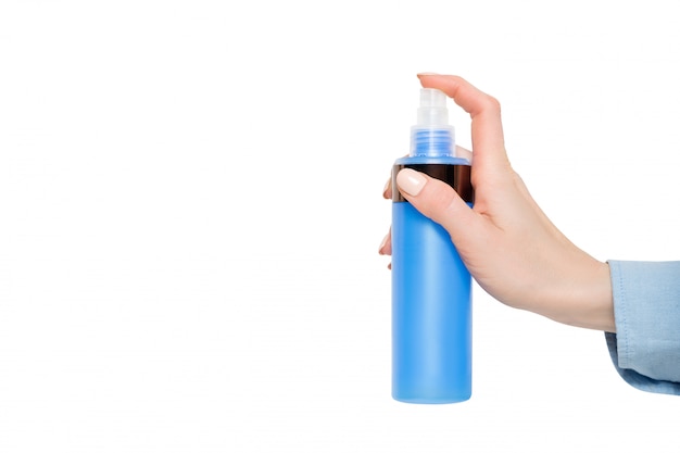 Spray de plástico azul para cosméticos em uma mão feminina. isolar