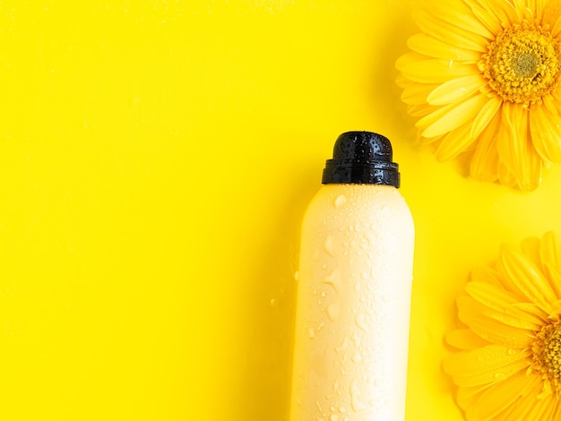 Spray de proteção solar amarelo e flores de margarida copiam o espaço