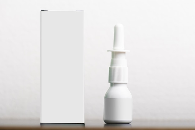 Spray nasal com uma caixa vazia no fundo branco