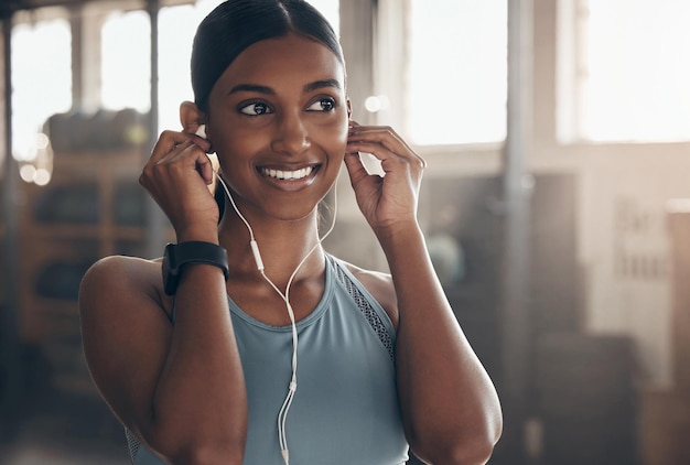 Sprengen Sie Ihre Lieblingsmusik und arbeiten Sie es aus. Aufnahme einer sportlichen jungen Frau, die Musik hört, während sie in einem Fitnessstudio trainiert.