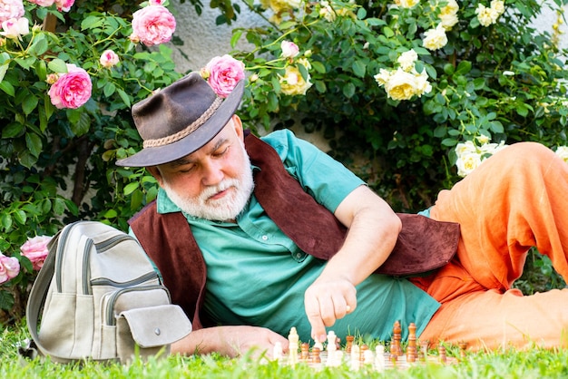 Spring park hombre maduro relajante en el jardín jardinero senior jugar al ajedrez al aire libre