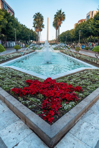 Springbrunnen und Blumen neben den Palmen in der Straße Belen der Rambla de Almeria, Andalusien. Spanien. Costa del Sol im Mittelmeer