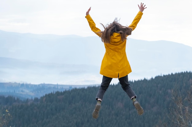 Springende junge Frau oben auf dem Berg Konzept der Freiheit Glückliche Touristenfrau eroberte die Spitze