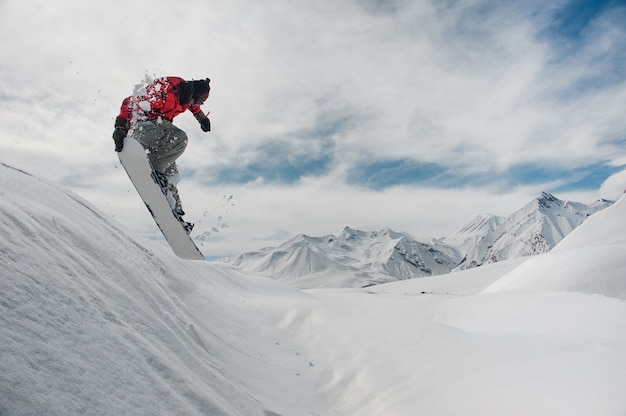 Springender Snowboarder, der seine Hand auf dem Snowboard hält