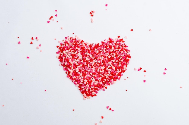 Sprinkles de perlas y grageas para la decoración de la torta en forma de corazón sobre fondo blanco.