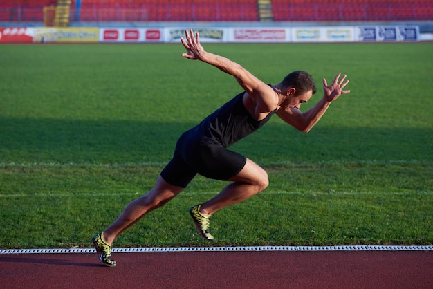 Sprinter deixando blocos de partida na pista de corrida. Arranque explosivo.