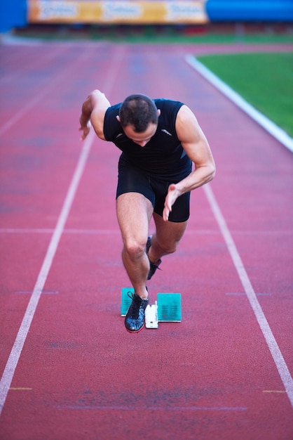 Sprinter deixando blocos de partida na pista de corrida. Arranque explosivo.