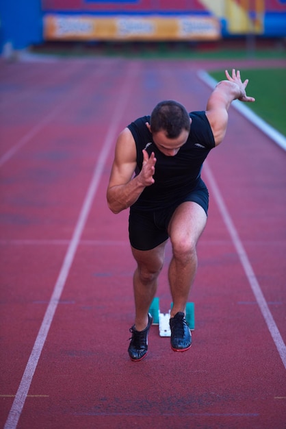 Sprinter deixando blocos de partida na pista de corrida. Arranque explosivo.