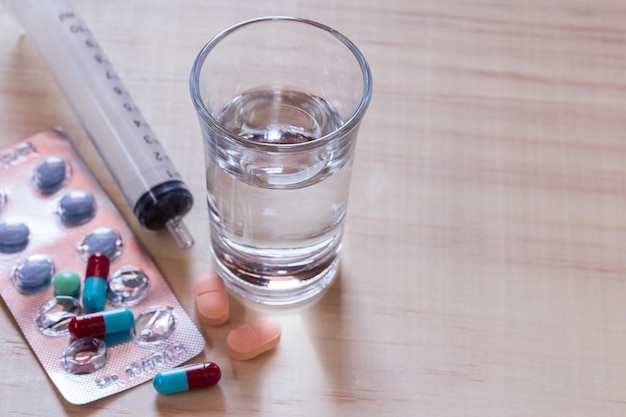 Spritze und Pillen mit Tabletten auf Holztisch hautnah