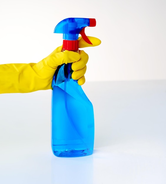 Spritzen und reinigen Schnappschuss einer Person, die vor grauem Hintergrund aus einer Flasche Reinigungsmittel sprüht