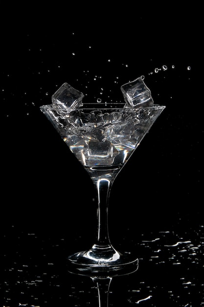 Spritzer Cocktail Martini mit Eis auf einem schwarzen Hintergrund