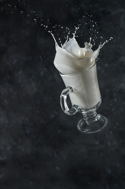 Spritzer Milch aus dem Glas auf grauem Hintergrund. Levitation.