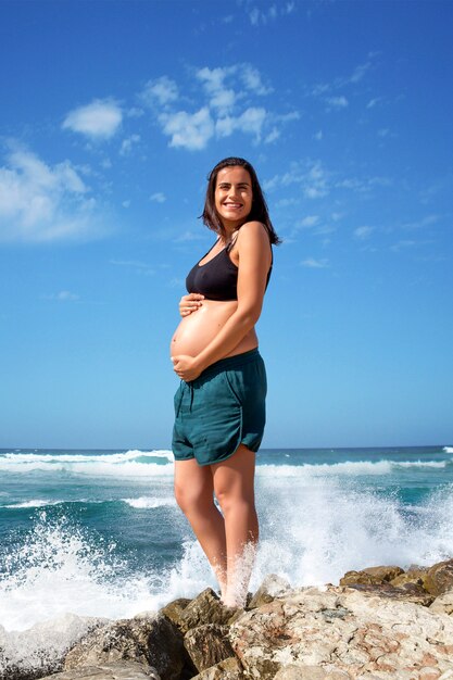 Spritzer Wasser hinter einer glücklichen schwangeren Frau