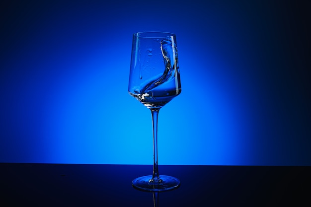 Spritzer Wasser in einem Glas auf blauem Grund.
