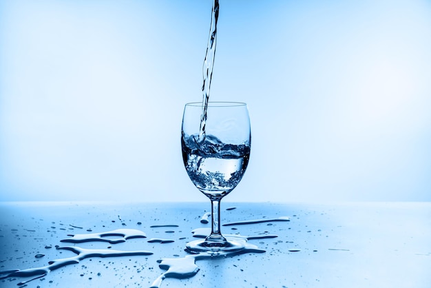 Spritzwasser aus Glas auf blauem Hintergrund isoliert