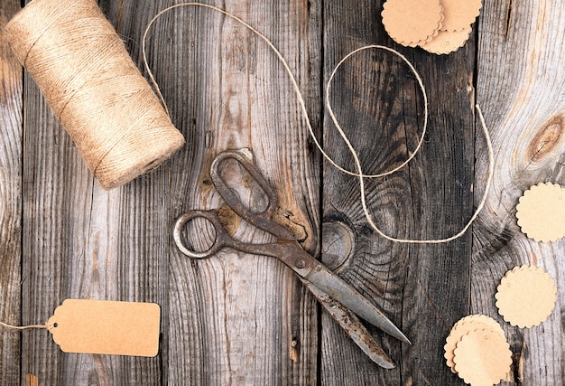 Spule des braunen seils, der papiertags und der alten scheren auf einem grauen holz