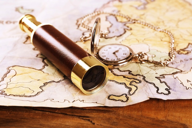 Spyglass-Taschenuhr und Weltkarte auf Holztischhintergrund