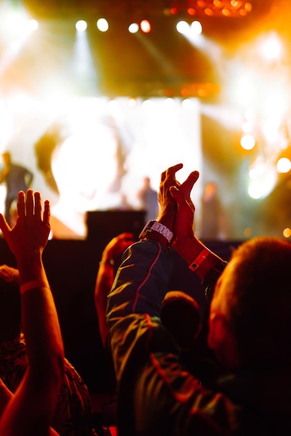 Srowd com as mãos levantadas no festival de música Fãs curtindo show de rock com show de luzes batendo palmas