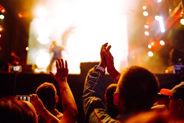 Srowd com as mãos levantadas no festival de música Fãs curtindo show de rock com show de luzes batendo palmas