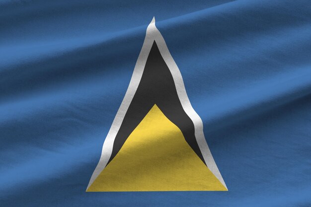 St. Lucia-Flagge mit großen Falten, die in der Nähe unter dem Studiolicht im Innenbereich winken Die offiziellen Symbole und Farben im Banner