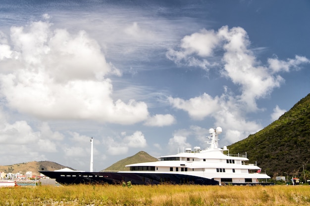 St Maarten, Holanda - 13 de febrero de 2016: barco de lujo o barco en la bahía cerca de la montaña soleada al aire libre sobre fondo de cielo nublado