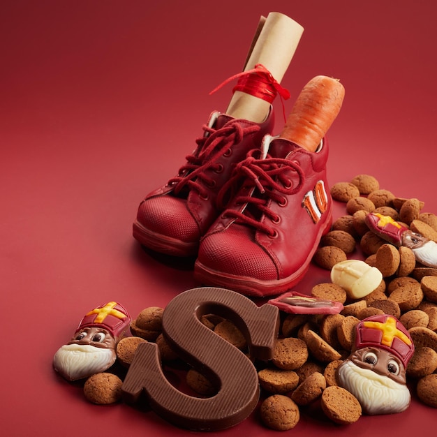 St. nikolaus sinterklaas tag mit schuhkarotte und traditionellen süßigkeiten auf rotem hintergrund