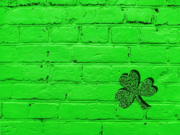Foto st. patrick's day alte grüne backsteinmauer mit grunge-textur und kleeblatt. abstraktes muster. heller hintergrund.