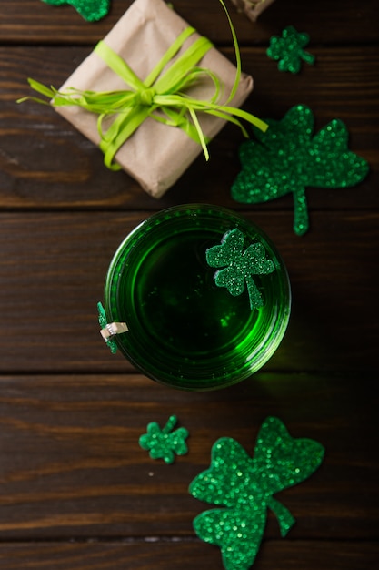 St. Patrick's Day Green Beer Pint über dunkelgrünem Tisch, dekoriert mit Kleeblattblättern. Patrick Day Pub Party, feiern.