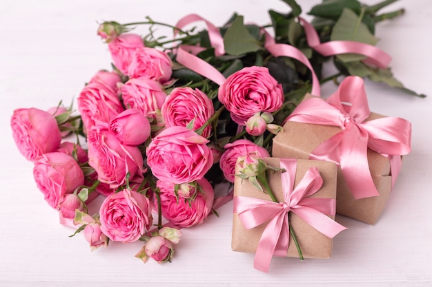 St. Valentinstag Konzept. Rosa Rosen und Geschenkboxen mit Bändern auf weißem Holztisch.