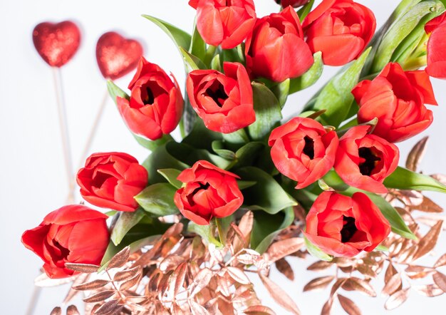 Foto st valentinstag zusammensetzung mit strauß tulpen und zwei roten herzen auf weißem hintergrund