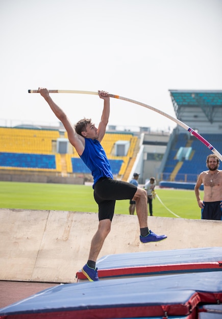 Foto stabhochsprung ein junger athletischer mann ruht auf der stange gegen den boden