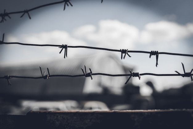 Stacheldrahtzaun gegen dramatischen, dunklen Himmel.